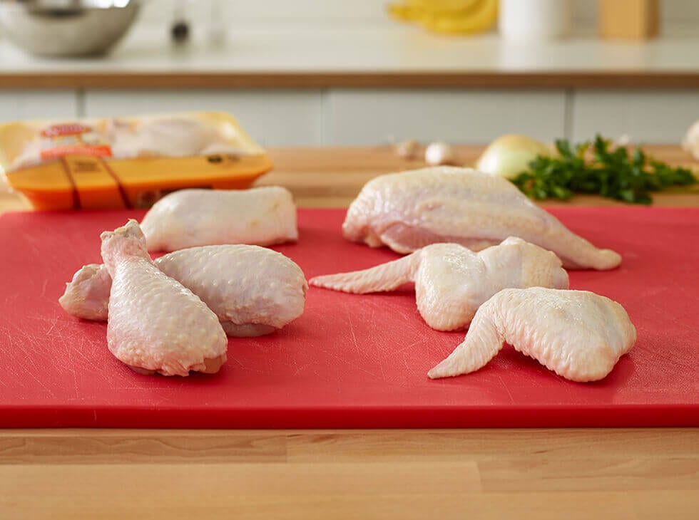 Raw chicken wings and drums laid out on a red cutting board